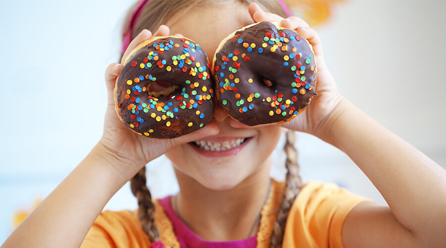 child holding up donuts to her eyes