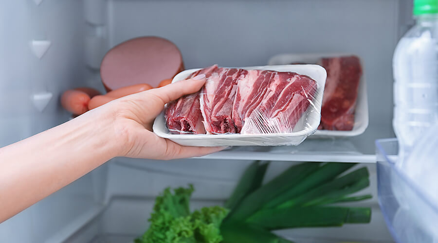 woman putting meat in fridge