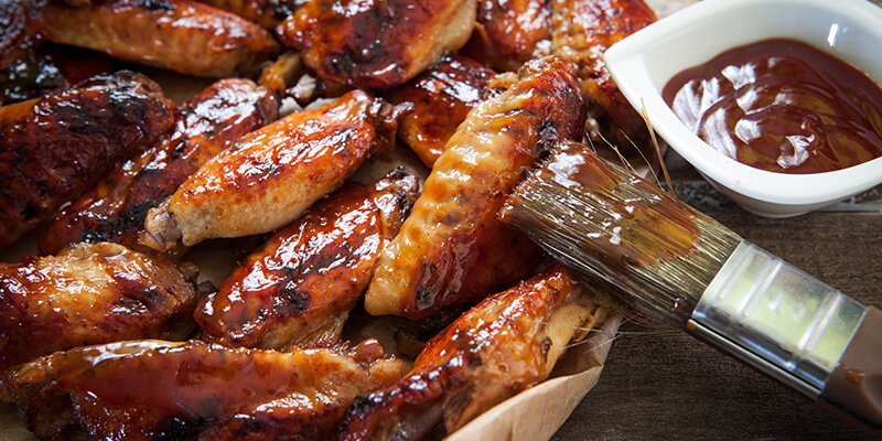 Brushing sauce on chicken wings